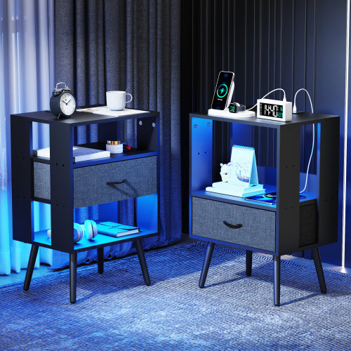 Two nightstands with electronic devices and items against a dark curtain background