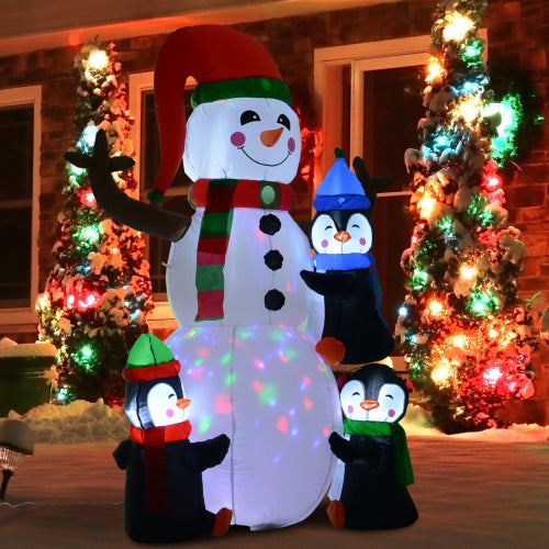 Inflatable snowman with penguins in front of a house decorated for Christmas.