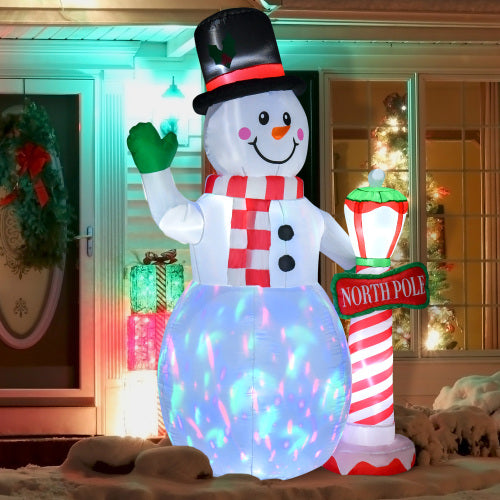 Inflatable snowman with a top hat and scarf, holding a 'North Pole' sign, in a festive indoor setting.